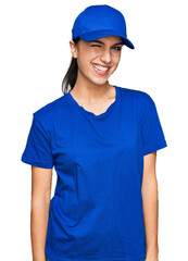 Young hispanic girl wearing delivery courier uniform winking looking at the camera with sexy...