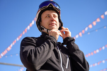 Skier Fastening Helmet Against Blue Sky - 774999766