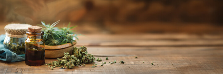 Cannabis (or hemp or marijuana) dried flower buds, bottle of CBD oil, medicinal legal cannabis web banner, natural alternative medicine on panoramic wood background - 775001184