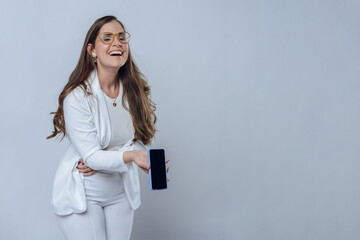 woman laughing out loud at message she heard on her phone, studio shot, copy space