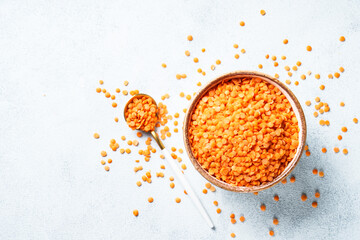 Red lentils in wooden bowl on white background.