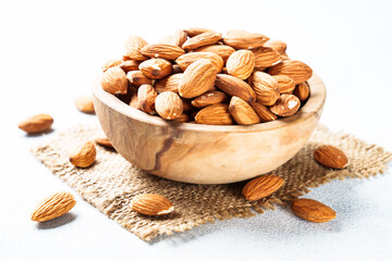 Almond nuts in wooden bowl at white background.