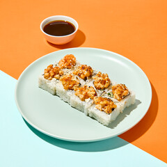Baked maki sushi in ceramic plate on coloured background. Sushi roll with shrimp tartare in trendy style on orange and blue colour backdrop Maki roll with hard shadows in minimal style