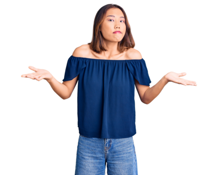 Young beautiful chinese girl wearing casual clothes clueless and confused expression with arms and hands raised. doubt concept.