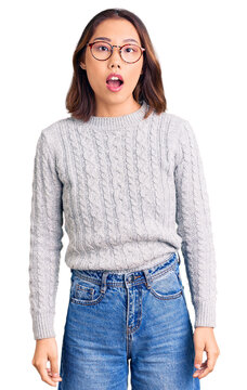 Young beautiful chinese girl wearing casual clothes afraid and shocked with surprise and amazed expression, fear and excited face.