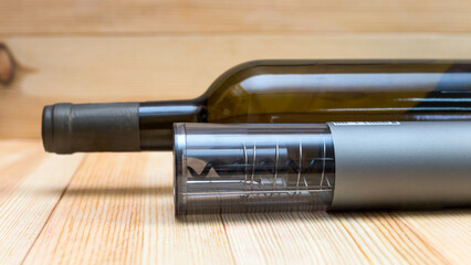 Electric corkscrew, wine bottle film opener on a light wood background.