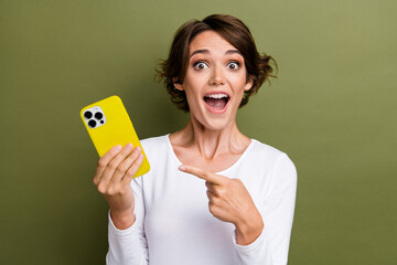 Photo portrait of lovely young lady hold point excited device dressed stylish white garment isolated on khaki color background