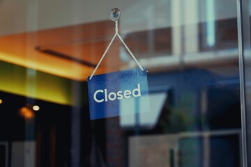 Closed sign hanging inside a glass door of the shop