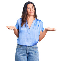 Young beautiful brunette woman wearing casual t-shirt clueless and confused expression with arms...