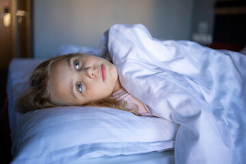 Portrait of a cute blonde little girl in her bed after a night's sleep. The benefits and proper...