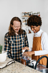 Young couple preparing morning coffee together in kitchen