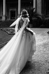 Back view of a bride wearing an elegant white wedding dress walking outdoors