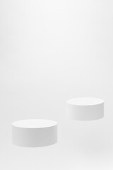 Set of two round white podiums for cosmetic products mockup, soar on white background. Stage for presentation skin care products, gifts, goods, advertising, design, sale in contemporary style.