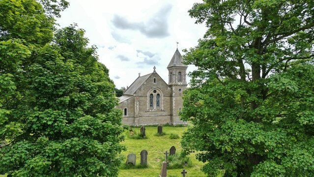 Disused Church of St Mary viewed from between trees in Foxholes, North Yorkshire, UK