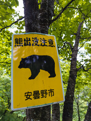 A sign warning of wild bears in Nagano, Japan. Text reads "Watch out for bears. Azumino City"
