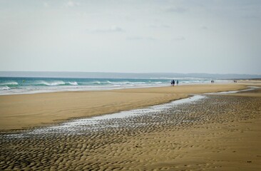 Sandy, summer beach with a boat and tourists
