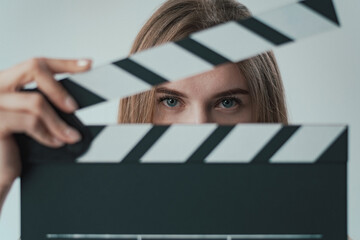 girl looks through the clapperboard at the camera