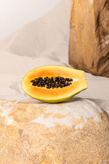 Half a papaya on beach. Vertical