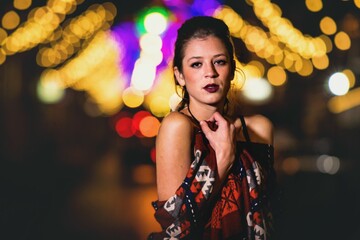 Caucasian woman posing with the blurred bokeh city lights at night