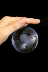 Vertical shot of a woman holding a small globe on the black background