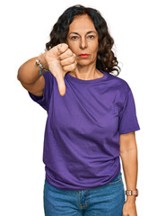 Middle age hispanic woman wearing casual clothes looking unhappy and angry showing rejection and negative with thumbs down gesture. bad expression.