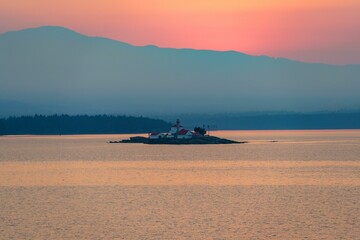 Obraz premium British Colombia sunset with red and white light house on an island