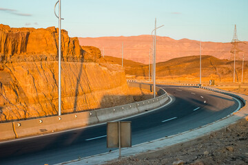 Highway turn passing through a rocky, desert landscape at sunset