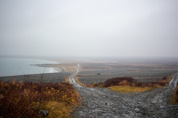 Barren landscape with water on the side, under gray foggy sky in Murmansk, Russia