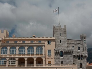 Fototapeta premium Low angle shot of a castle with a flag and a cloudy sky in Monaco, Monte Carlo