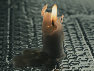 White candle on ground with water droplets