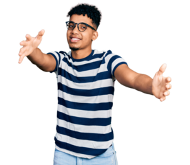 Young african american man wearing casual clothes and glasses looking at the camera smiling with open arms for hug. cheerful expression embracing happiness.
