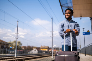 Happy man with suitcase standing on railway station.	 - 775038761
