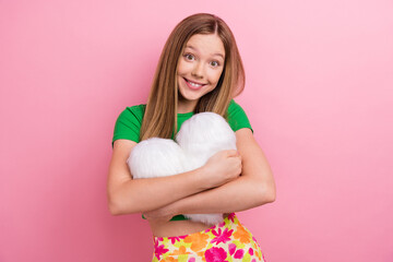 Photo portrait of pretty teenager girl hugging heart pillow dressed stylish green outfit isolated on pink color background