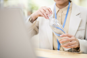 Office white-collar worker holds mineral water bottle and drinks water