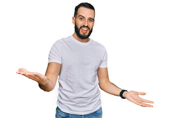 Young man with beard wearing casual white t shirt smiling cheerful with open arms as friendly welcome, positive and confident greetings
