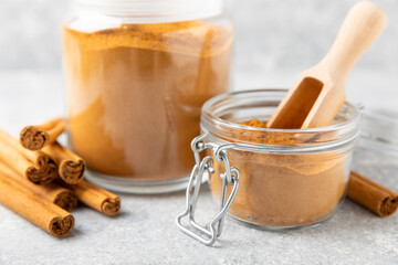 Cinnamon powder in a bowl on a textured wooden background. Spicy spice for baking, desserts and drinks. Fragrant ground cinnamon. Cinnamon stick. Place for text. Copy space.