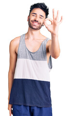 Young hispanic man wearing casual clothes smiling positive doing ok sign with hand and fingers. successful expression.