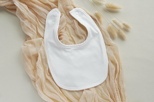White baby bib mockup for design presentation, bohemian style flat lay, pregnancy announcement.
