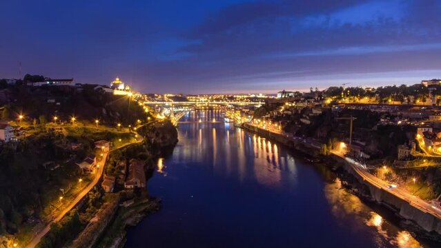 Day to night transition aerial view of the historic city of Porto, Portugal timelapse panorama with the Dom Luiz bridge. Illuminated waterfront and curved river from above