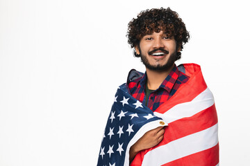 Happy young Hindi man covered in American flag isolated over white background. Handsome Indian boy...