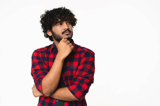 Pensive young Indian man in casual clothes thinking about future isolated over white background. Attractive Hindi boy contemplating about plans, having idea, choosing