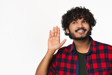 Young Hindi man listening to rumors isolated over white background. Cheerful Indian boy in casual...