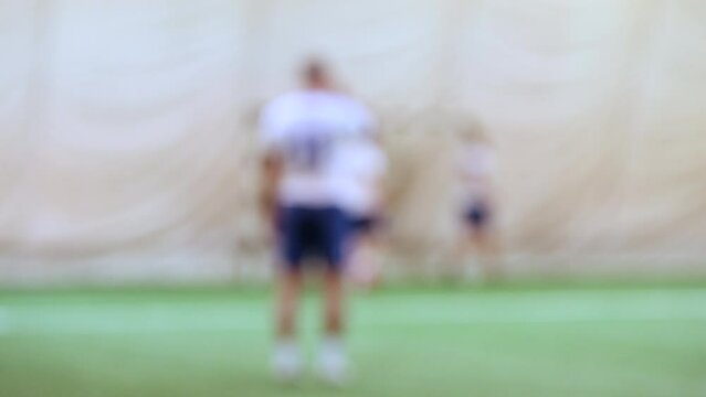 Five-a-side soccer players playing game in indoor stadium on artificial turf.