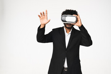 Modern Indian businessman in formal black tuxedo playing games with VR glasses isolated over white...