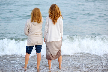 Redhead senior mother and her beautiful adult daughter are walking together. A happy meeting of a...