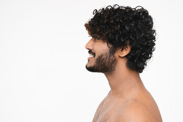 Side view portrait of young handsome Hindu man shirtless smiling isolated over white background....
