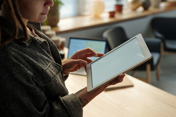 Cropped shot of young female owner of cafe or coffee shop holding tablet with blank screen while...