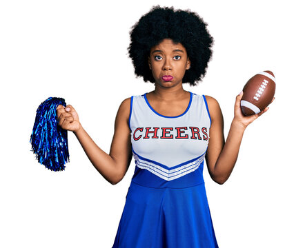 Young african american woman wearing cheerleader uniform holding pompom and football ball depressed and worry for distress, crying angry and afraid. sad expression.