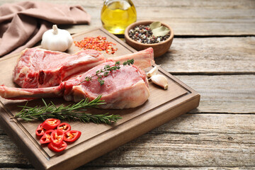 Fresh tomahawk beef cuts and spices on wooden table. Space for text