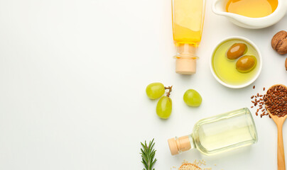 Vegetable fats. Different oils in glass bottles and ingredients on white table, flat lay. Space for...